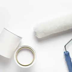 Pennello e barattolo di pittura bianca, pronti per dipingere. Valutare i pittura al quarzo svantaggi prima di iniziare.