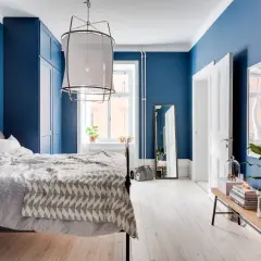 Accogliente camera da letto blu con letto comodo, armadio capiente e specchio a figura intera.