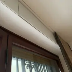 Dettaglio di un cassonetto tapparelle in fase di rimozione, con pannello in legno appoggiato.