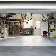 Organizzazione garage con scaffalature, biciclette appese e attrezzi. Ottime idee garage fai da te per uno spazio funzionale.
