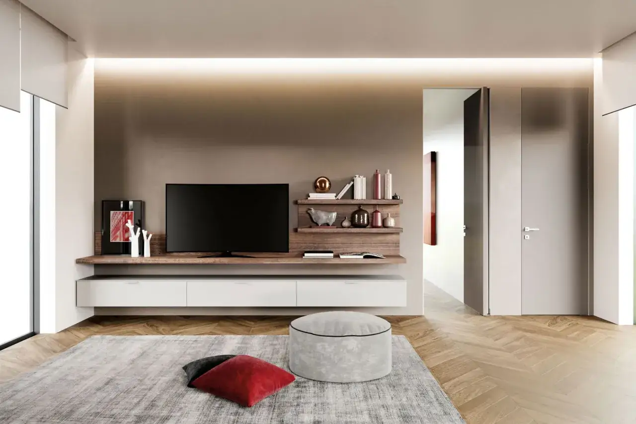 Soggiorno moderno con mobile TV sospeso, mensole in legno e pouf. Pareti color tortora e porta grigia.
